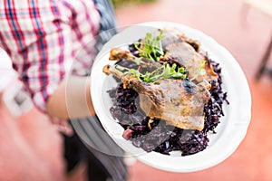 Waiter with large platter- duck confit and wine braised cabbage photo