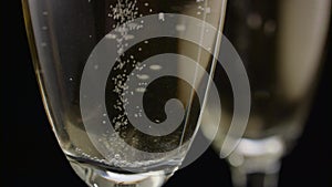 Waiter makes a glass with sparkling champagne. Black background. Close up