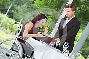 Waiter making recommendation to woman in wheelchair