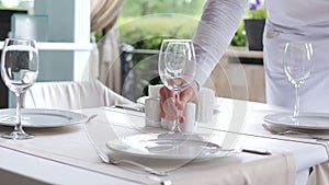 A waiter in a medical protective mask serves the table in the restaurant