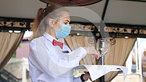 A waiter in a medical protective mask serves the table in the restaurant