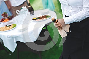 Waiter opens a bottle of champagne, wine.