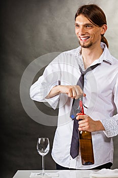 Waiter opens wine bottle.