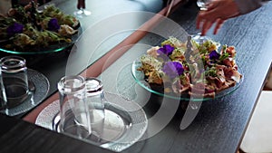 waiter places a set of seafood canapes, prawns, meat on a large tray on the room table for diners in the luxury