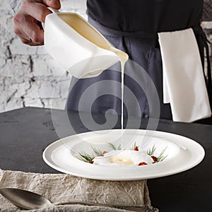 Waiter pouring broth to mushroom cream soup