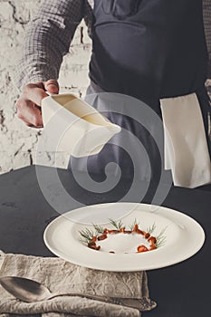 Waiter pouring broth to mushroom cream soup