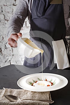 Waiter pouring broth to mushroom cream soup