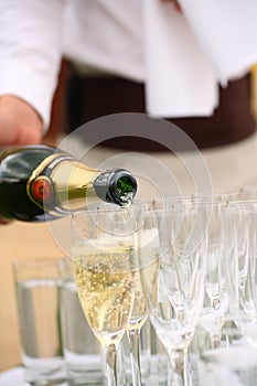 Waiter pouring champagne in glasses on the table