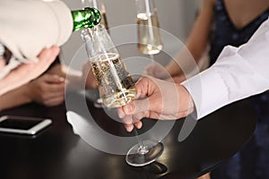 Waiter pouring champagne into man`s glass at party