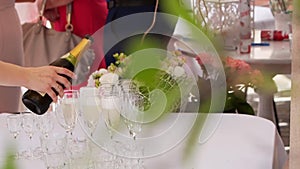 Waiter pouring champagne to glasses on celebration event in restaurant outdoors. Sparkling white whine on birthday party