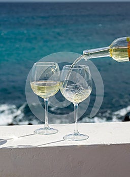 Waiter pouring glass of white wine on outdoor terrace with sea v