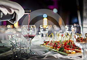 Waiter pouring red wine into a glass in cafe