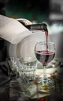 Waiter pouring red wine into a glass in cafe