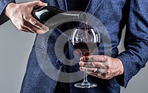 Waiter pouring red wine in a glass. Sommelier man, degustation, winery, male winemaker. Red wine is poured from bottle