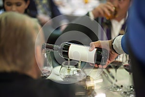 Waiter pouring red wine in wine glass on the table for service.