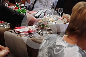 Waiter pouring wine in glass of guest at luxury stylish decorate