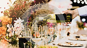 Waiter pouring wine into glass at luxury wedding
