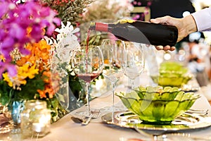 Waiter pouring wine into glass at luxury wedding