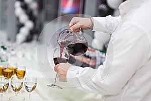 The waiter pours champagne into a glass.Empty glasses on the white table, A row of empty champagne