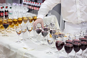 The waiter pours champagne into a glass.Empty glasses on the white table, A row of empty champagne