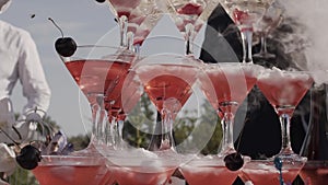 The waiter pours champagne in glass tower.