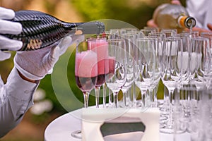The waiter pours champagne into glasses for a party, red wine in glasses, champagne at a celebration