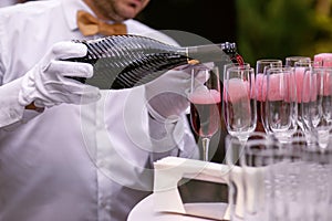 The waiter pours champagne into glasses for a party, red wine in glasses, champagne at a celebration