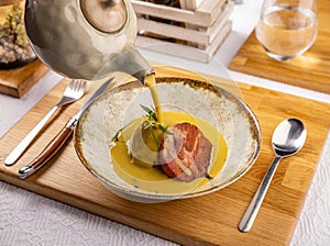 Waiter pours cream soup into a baked potato