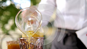 Waiter pours orange juice into a glass in close-up. Beautiful breakfast in a hotel