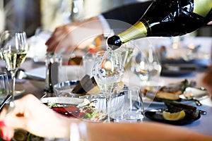 The waiter pours white wine into a glass. Banquet, cutlery, table setting. photo