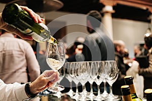 A waiter pours wine from a bottle into a glass