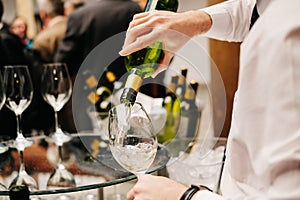 A waiter pours wine from a bottle into a glass