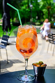 Waiter prepared the Aperol Sprits summer cocktail with Aperol, prosecco, ice cubes and orange in wine glass, ready to drink on