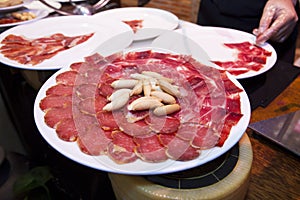 Waiter is preparing spanish cured iberico ham and loin slices on