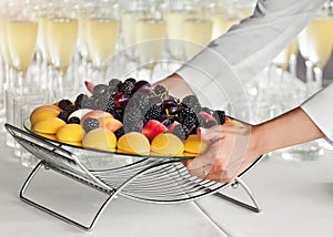 Waiter putting fruit tray on table at party