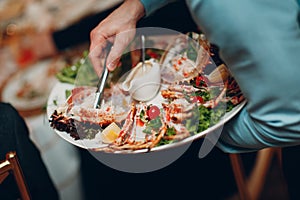 a waiter in a restaurant holds seafood dishes and serves a table catering Concept Healthy food octopus and crabs