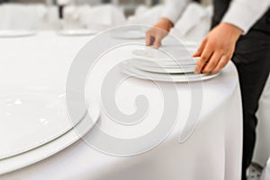 The waiter in the restaurant serves the dining table. Close up restaurant setting. Out of focus, blur photo