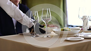 Waiter`s hand in a glove bringing white plate of food to male customer.