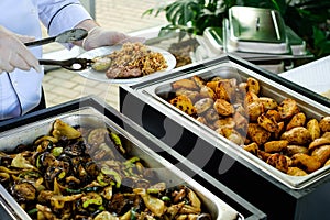 Waiter`s hands in sterile gloves with tongs and hot food