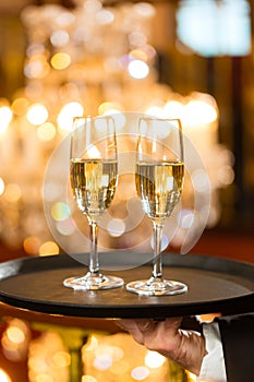 Waiter served champagne glasses on tray in restaurant