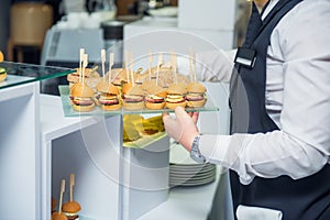 The waiter is servering catering buffet table with food and snacks for guests of the event. Dining Food Celebration Party Concept.