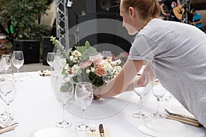 The waiter serves banquet table. Wedding table setting decorated with flowers and brass candlesticks with candles