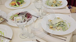 The waiter serves dishes to put on the table in the restaurant. Male waiter in a restaurant puts plates of hot meat dish