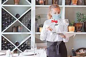 The waiter serves a table in a cafe in a protective mask photo