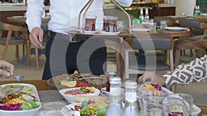 A waiter serves a table with food in a restaurant