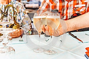 The waiter serves two glasses of white wine for a couple.  Man and woman have a lunch on a restaurant