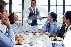 Waiter serving coffee to business people