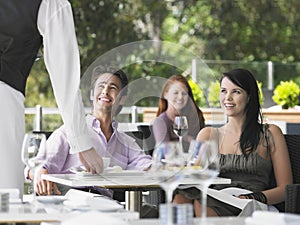 Waiter Serving Coffee To Young Couple At Cafe