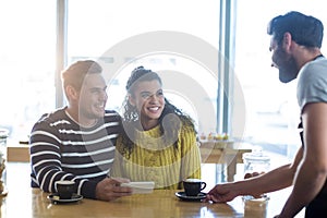 Waiter serving a cup of coffee to customer