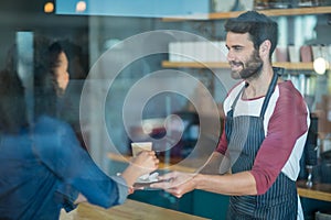 Waiter serving a cup of cold coffee to customer at counter